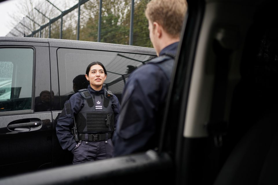 en kvindelige og mandlig transportbetjent står og taler sammen ved en transportbil